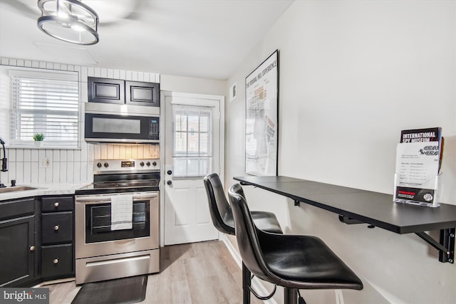 kitchen featuring appliances with stainless steel finishes, sink, and light hardwood / wood-style flooring