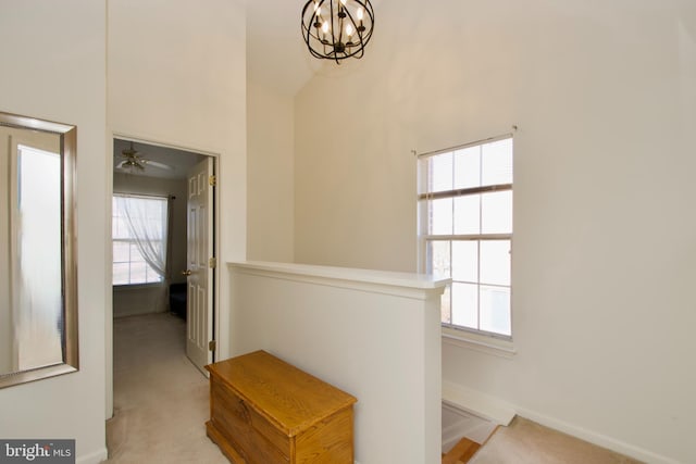 hall featuring a chandelier, baseboards, an upstairs landing, and light colored carpet