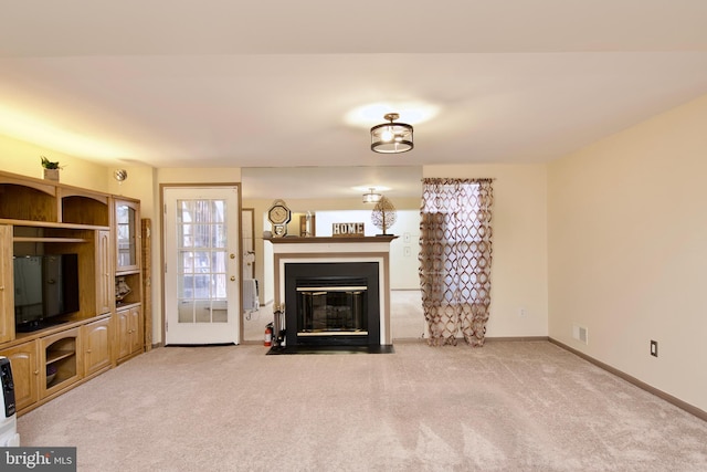 unfurnished living room featuring a fireplace with flush hearth, carpet flooring, visible vents, and baseboards