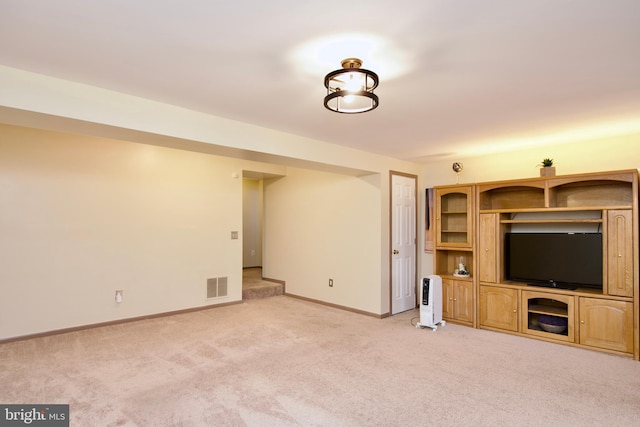 unfurnished living room with baseboards, visible vents, and light colored carpet