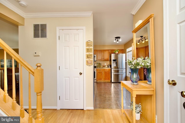 interior space featuring stairs, ornamental molding, light wood-style flooring, and visible vents