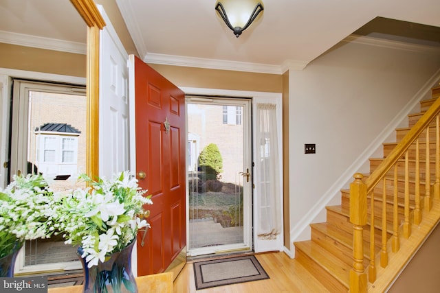 entryway featuring light wood-style flooring, crown molding, and stairway