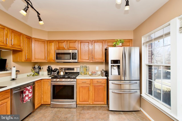 kitchen with light tile patterned floors, stainless steel appliances, light countertops, and rail lighting