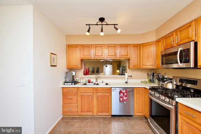 kitchen featuring baseboards, stainless steel appliances, a sink, and light countertops