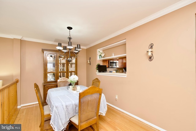 dining space with light wood-style floors, baseboards, ornamental molding, and a chandelier