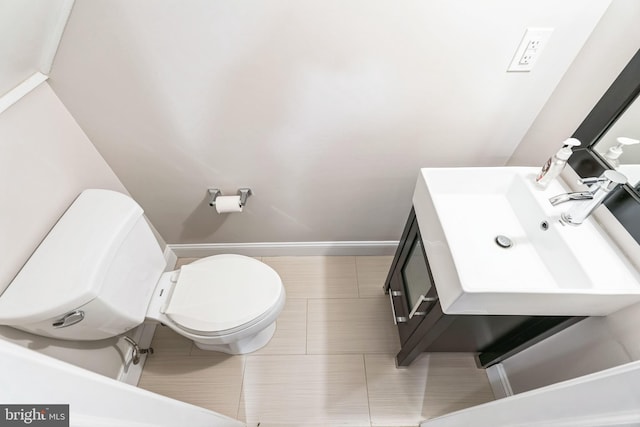 half bathroom featuring toilet, tile patterned flooring, baseboards, and vanity