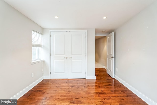 unfurnished bedroom featuring recessed lighting, a closet, baseboards, and wood finished floors