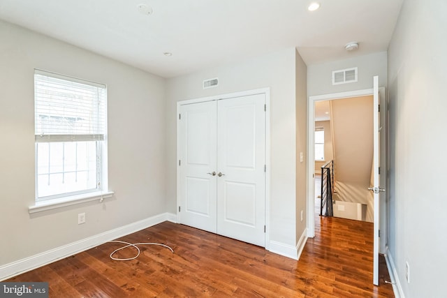 unfurnished bedroom featuring a closet, wood finished floors, and visible vents