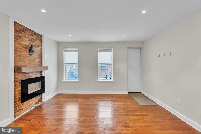 unfurnished living room featuring a large fireplace, recessed lighting, wood finished floors, and baseboards