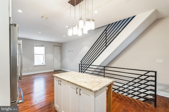 interior space featuring a kitchen island, white cabinetry, baseboards, dark wood-style floors, and pendant lighting