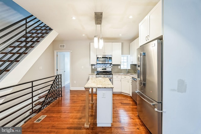 kitchen with visible vents, decorative backsplash, dark wood-type flooring, stainless steel appliances, and a kitchen bar