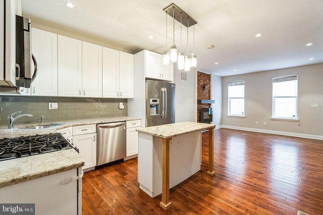 kitchen featuring stainless steel appliances, hanging light fixtures, dark wood-style floors, and tasteful backsplash