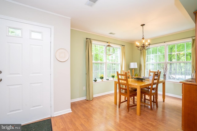 dining room with light wood-type flooring, crown molding, baseboards, and a chandelier