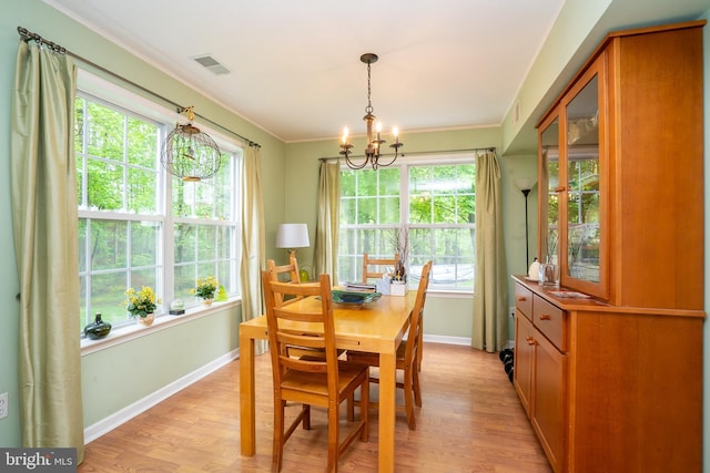 dining area with a chandelier, light wood-style flooring, healthy amount of natural light, baseboards, and crown molding