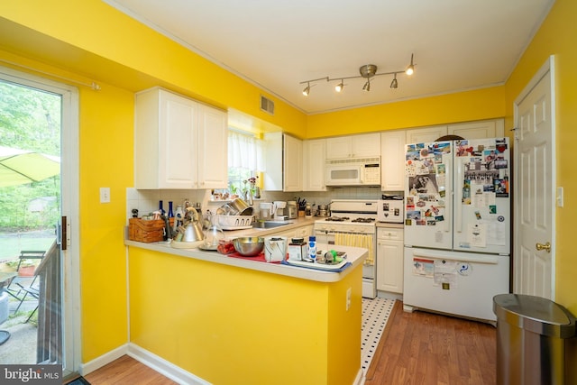 kitchen with white appliances, a peninsula, decorative backsplash, white cabinets, and light countertops