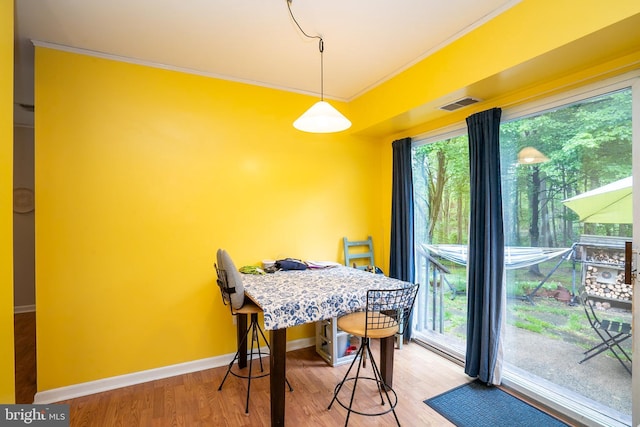 dining area with light wood-style flooring, crown molding, and baseboards