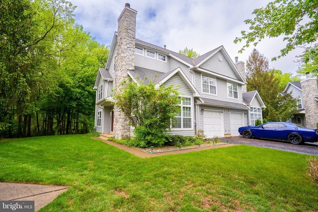 view of front of house with a chimney, an attached garage, asphalt driveway, and a front yard