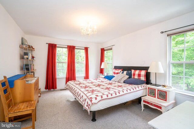 bedroom with multiple windows, carpet floors, and a chandelier