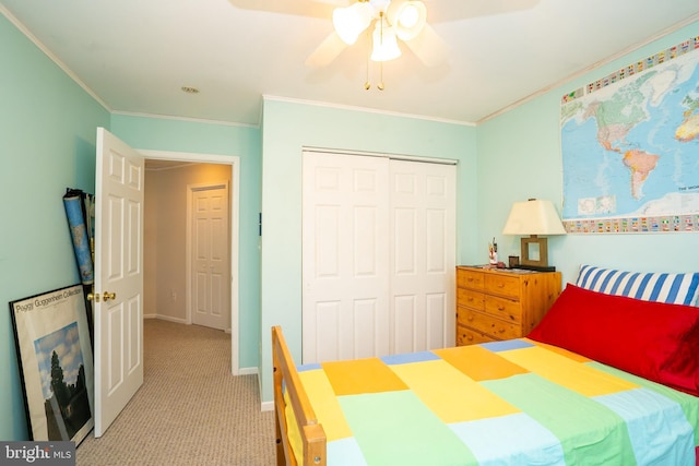 bedroom with light colored carpet, crown molding, a closet, baseboards, and a ceiling fan