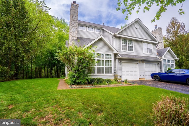 view of front of house with a chimney, a garage, driveway, and a front lawn