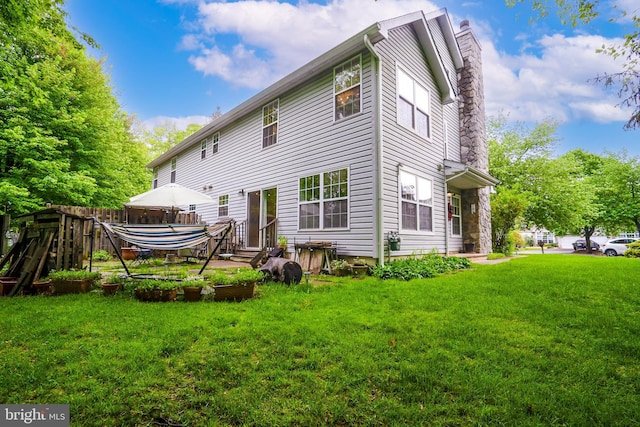 back of property with a chimney, a yard, and entry steps