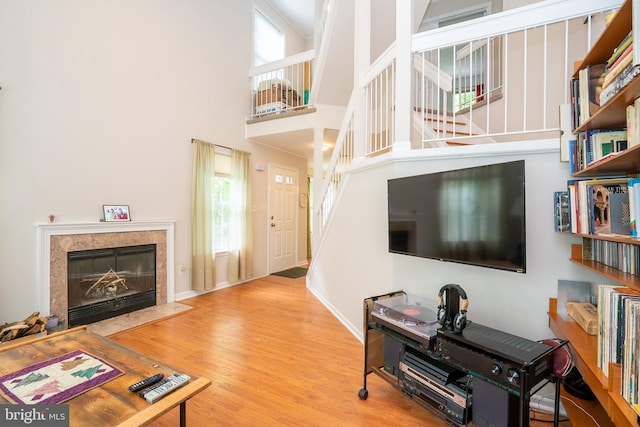 living room featuring stairway, wood finished floors, a premium fireplace, a towering ceiling, and baseboards