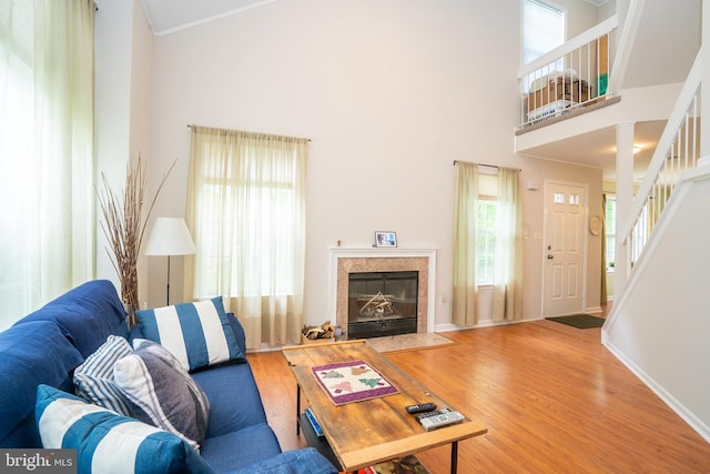 living room with wood finished floors, stairs, a fireplace, baseboards, and ornamental molding