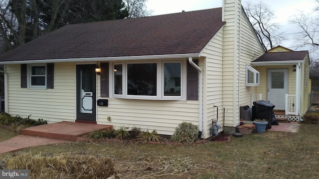 view of front of house with roof with shingles and a chimney