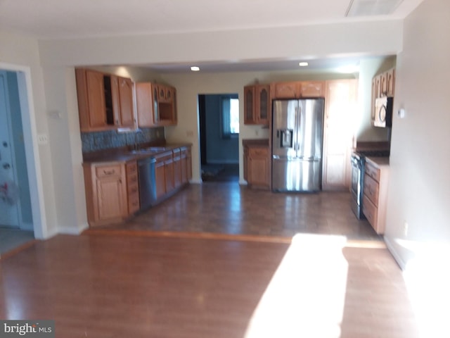 kitchen featuring appliances with stainless steel finishes, hardwood / wood-style floors, and backsplash