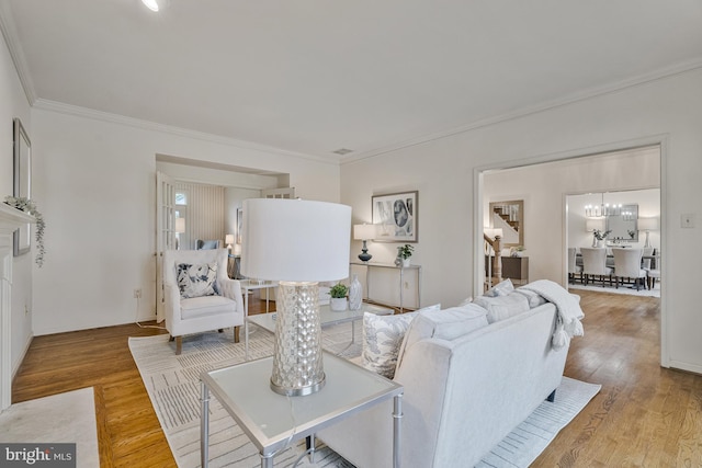 living room with crown molding, wood finished floors, and a notable chandelier