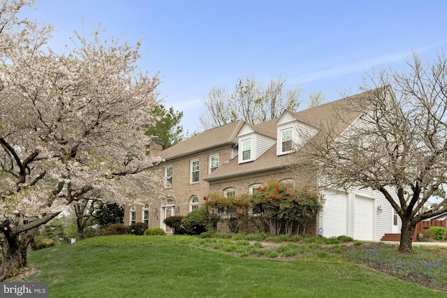 colonial home with a garage, brick siding, and a front lawn