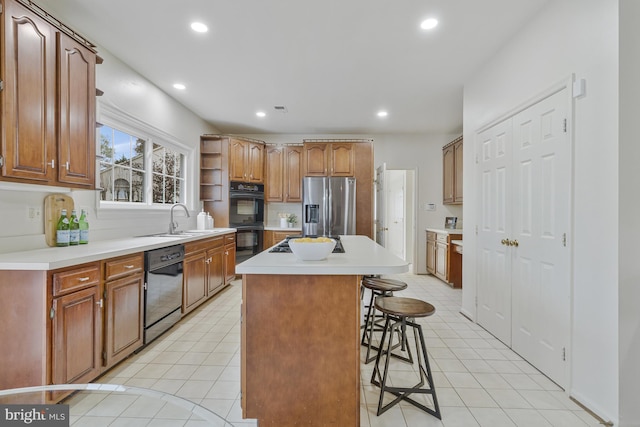 kitchen with black appliances, a center island, light tile patterned flooring, a sink, and a breakfast bar area