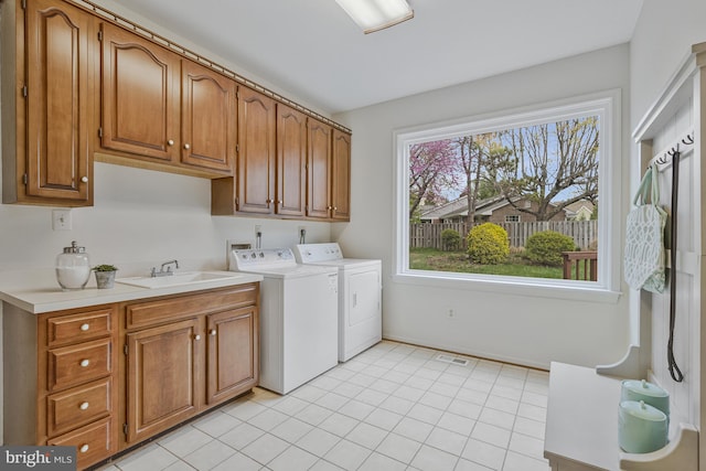 laundry room with light tile patterned floors, a sink, cabinet space, and washing machine and dryer