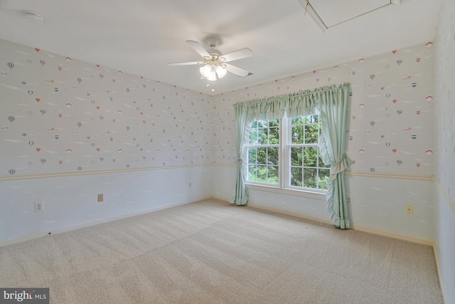 spare room featuring baseboards, wallpapered walls, attic access, a ceiling fan, and carpet floors