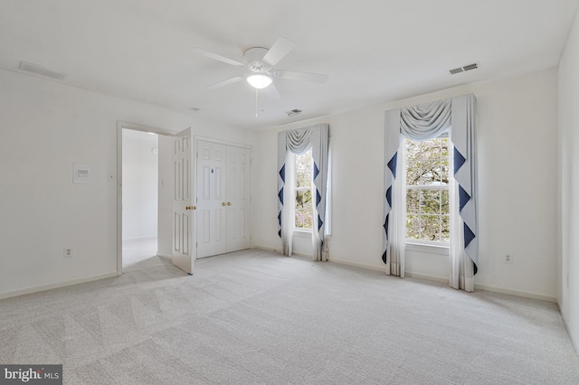 carpeted spare room featuring visible vents, ceiling fan, and baseboards