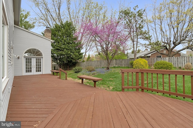 wooden terrace featuring french doors, a fenced backyard, and a lawn