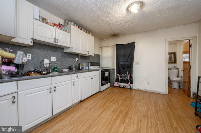 kitchen with sink, white range with gas stovetop, white cabinetry, light hardwood / wood-style floors, and tasteful backsplash