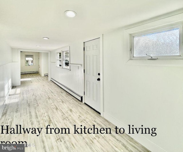 hallway featuring a baseboard heating unit and light hardwood / wood-style flooring