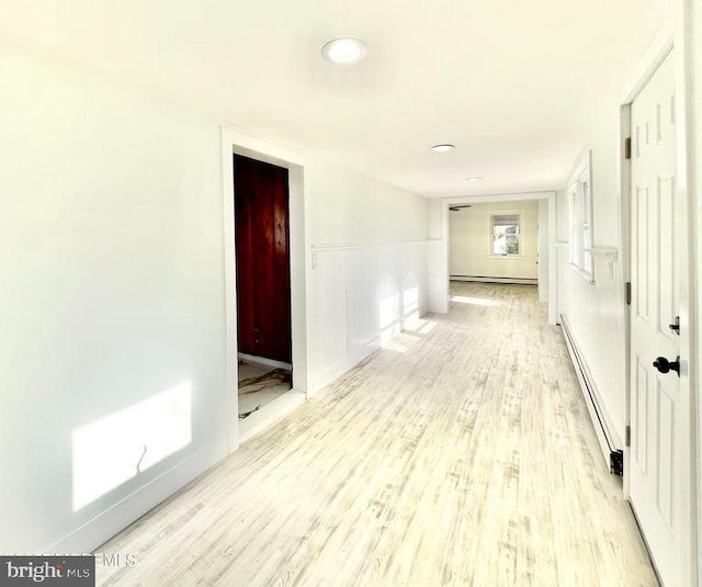 corridor featuring light wood-type flooring and a baseboard radiator