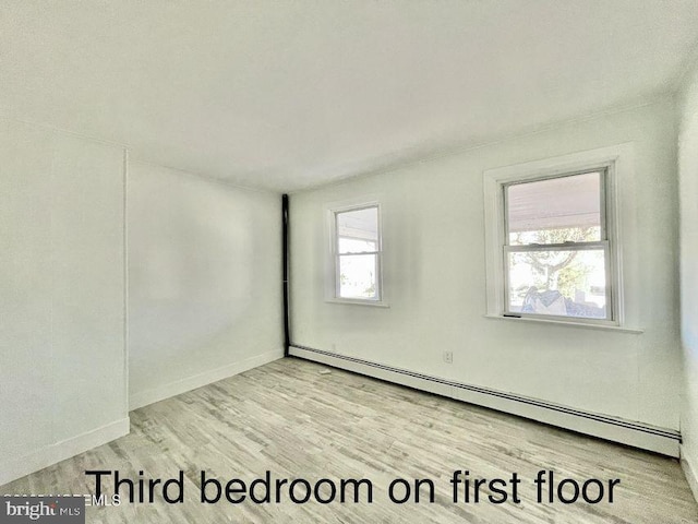 unfurnished room featuring baseboard heating and light hardwood / wood-style flooring