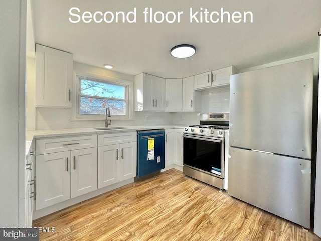 kitchen with stainless steel appliances, decorative backsplash, light hardwood / wood-style floors, sink, and white cabinetry