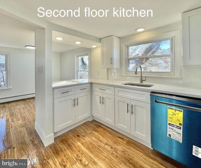 kitchen with white cabinetry, light wood-type flooring, dishwashing machine, sink, and a baseboard radiator