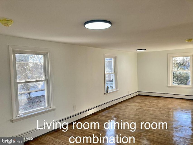 spare room with a healthy amount of sunlight, baseboard heating, and hardwood / wood-style flooring