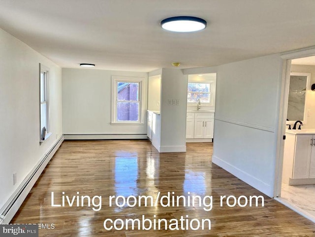 unfurnished room featuring hardwood / wood-style flooring, sink, and a baseboard radiator