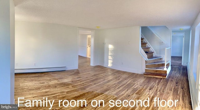 empty room with dark hardwood / wood-style flooring, a textured ceiling, and a baseboard heating unit