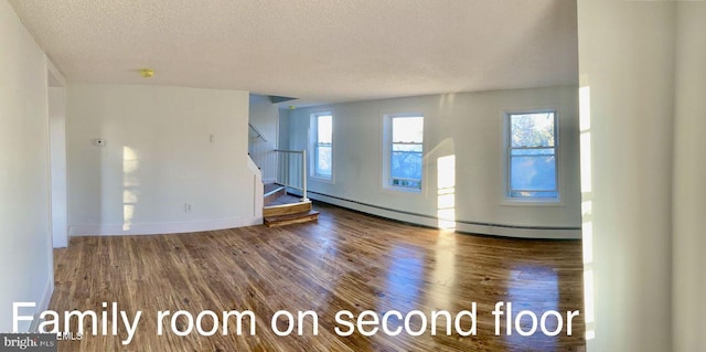 unfurnished living room featuring hardwood / wood-style flooring, a textured ceiling, and a baseboard heating unit