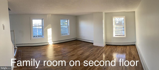 interior space featuring baseboard heating, dark hardwood / wood-style flooring, and a textured ceiling