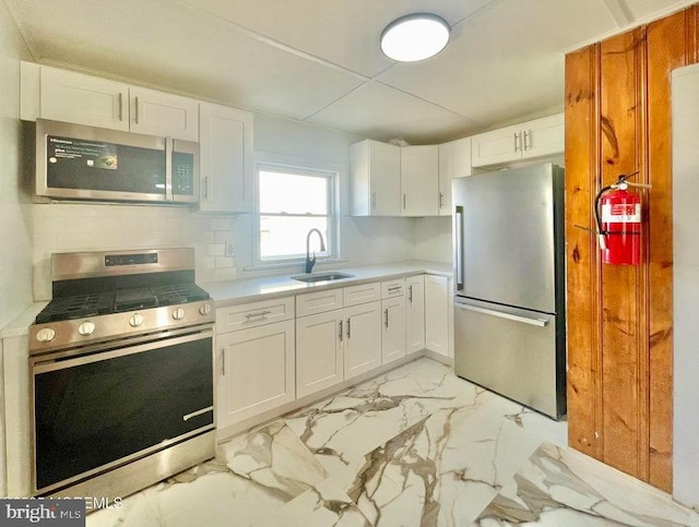 kitchen with appliances with stainless steel finishes, sink, white cabinetry, and tasteful backsplash