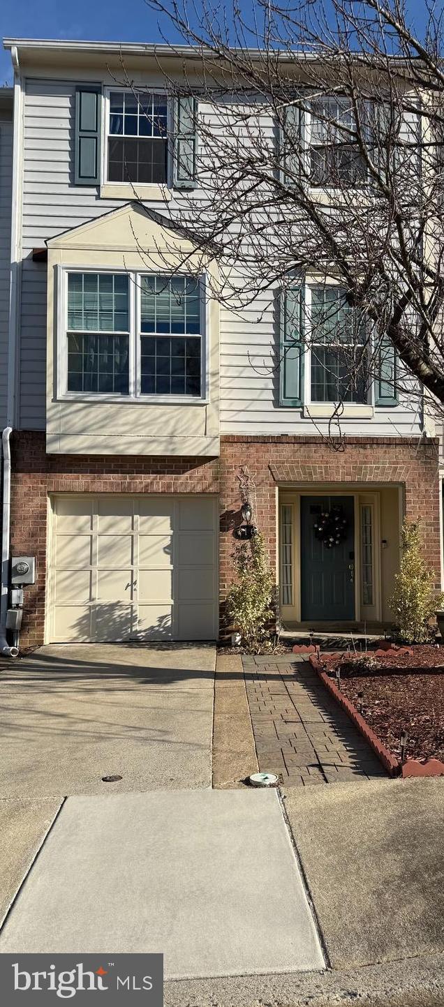 multi unit property featuring concrete driveway, brick siding, and an attached garage