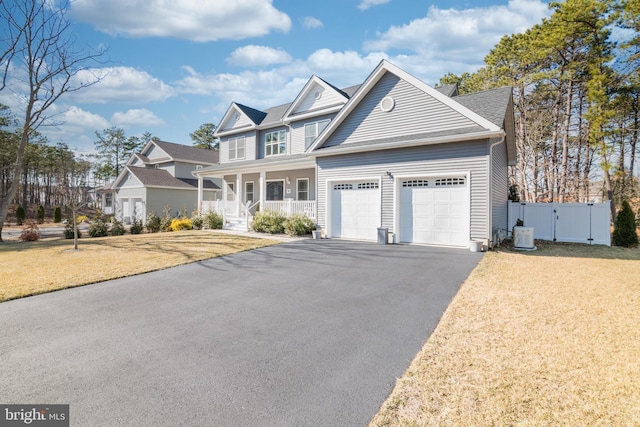 view of front of property with a garage, aphalt driveway, covered porch, a gate, and a front yard